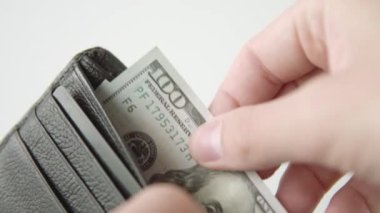 Mans el beyaz arka planda siyah deri bir cüzdan Amerikan para birimini çeker. Nakit ödeme konsepti ve Amerikan doları. Yakın görünüm.