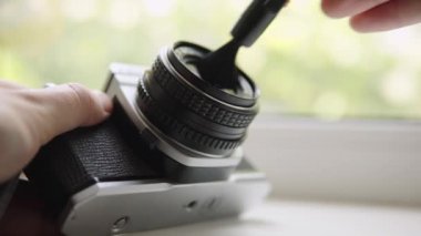 Servis elemanı eski kamera lenslerini fırçayla temizliyor. Profesyonel fotoğraf ekipmanları. Kamera bakım ve onarım. Yüzeyin derinliği. Yakın plan..
