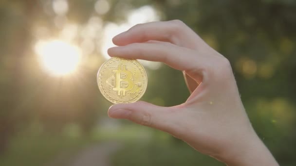 Man Shows Bitcoin Coin Cryptocurrency Symbol Background Green Blurred Trees — Vídeo de Stock