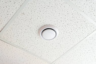 Smoke detector on the ceiling of an office building or a room in a residential building, apartment. Close up shot.