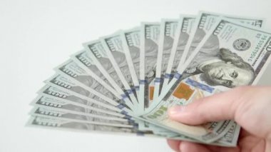 Man holds a fan of 100 dollar bills, many cash bills, thousand dollars. Close up shot, selective focus, white background.