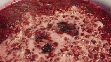 Evde, ocağın üzerinde iştah açıcı ahududu reçeli yaparken. Yüksek kalite 4k görüntü.