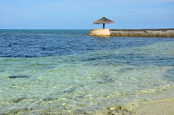 Indian ocean with marine pier and beach umbrella Maldives — Stock Photo, Image