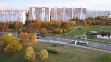 Günbatımında Avrupa şehir merkezinde toplu taşımacılık ile birlikte havadan izlenen yol. Konut binalarının arka planında renkli sonbahar ağaçları var. Güzel manzara. 10.01.2021 Minsk Belarus