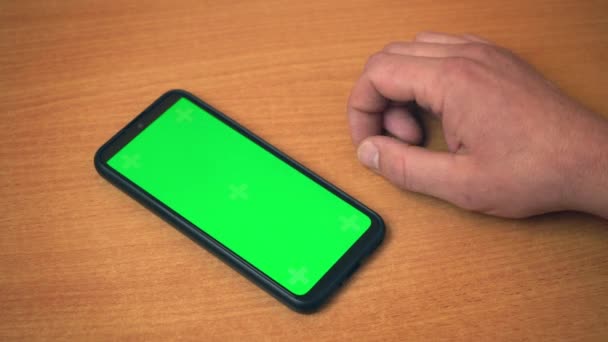 Вид сверху на мужские руки, держащие мобильный телефон с зеленым макияжным экраном. Белый мужчина использует современный смартфон на рабочем месте. Серфинг в Интернете, просмотр блогов на центральном экране 4k — стоковое видео