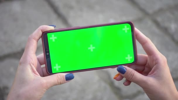 Γυναίκα κατέχει το κινητό τηλέφωνο και κάντε κλικ στην οθόνη σαρώνει φωτογραφίες ή φωτογραφίες στο δρόμο στο παρασκήνιο των πλακών πλακόστρωσης. Εικονογράφηση πλήκτρων Chroma στο smartphone στο χέρι. Χρήση πράσινης οθόνης για αντιγραφή χώρου closeup 4k — Αρχείο Βίντεο
