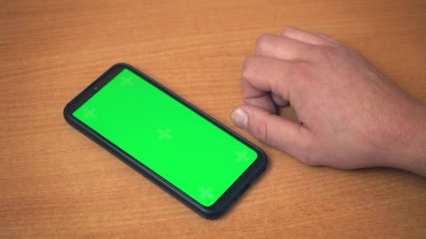 Вид сверху на мужские руки, держащие мобильный телефон с зеленым макияжным экраном. Белый мужчина использует современный смартфон на рабочем месте. Серфинг в Интернете, просмотр блогов на центральном экране 4k — стоковое видео