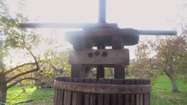 Starý dřevěný lis na výrobu čerstvě vymačkaného džusu na pozadí slunečního světla. Stlačování čerstvých jablek v dřevěném lisu na kýbl k výrobě jablečného moštu ve vesnici. Zpracování potravin 4k — Stock video