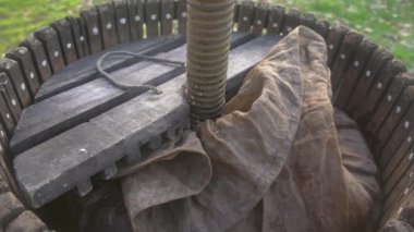 Erkeklerin elleri kapalı elma suyu alkolü hasadı için ahşap pres aleti oluşturun. Köyde üretmek için kovaya taze elma sıkıştırıyorum. Meyve ambalajı, gıda işleme deposu 4K