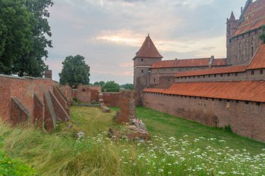 Polonya 'nın Malbork şehrinde bulutlu bir günde Tötonik Düzen Kalesi' nde gün batımı manzarası. Malbork Şatosu dünyanın en büyük şatosudur..