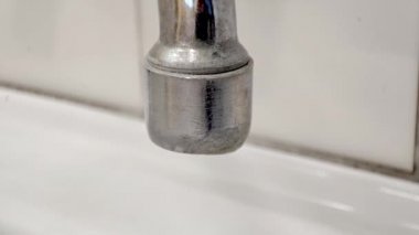 Damlayan su damlalarıyla eski musluğu kapat.