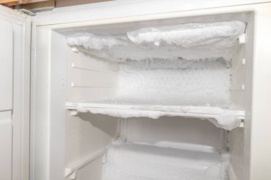 Ice inside a fridge. Defrosting freezer. clipart