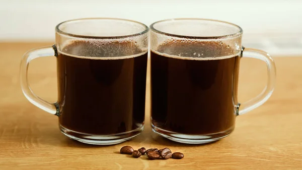 目の前に豆と木製のテーブルの上のガラスカップで2杯のコーヒードリンク — ストック写真