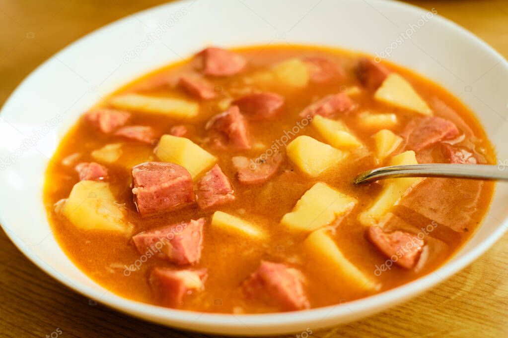 Tasty traditional czech goulash soup with sausages and potatoes burtgulas in white bowl
