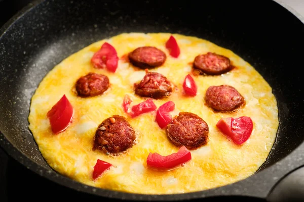 在煎锅里用西红柿片腊肠烹调美味的煎蛋卷 — 图库照片