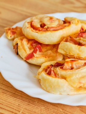 Tasty pizza rolls with ham and cheese on white plate