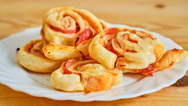 Tasty pizza rolls with ham and cheese on white plate