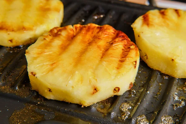 Preparing grilled pineapple fruit on grill close up