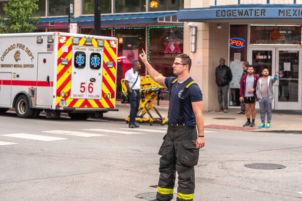 Chicago, IL - October 6th, 2021: A fireman helps direct traffic after a construction pile driving drill rig tips over while doing work near the Bryn Mawr CTA train station and tracks.