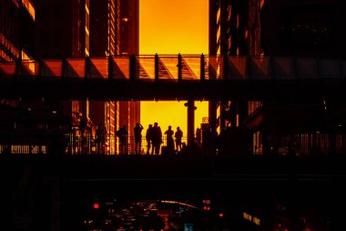 Şikago, IL - 23 Eylül 2021: Fotoğrafçılar, Washington ve Wabash CTA platformunda, şehirde turuncu bir renk alan ve uzun gölgeler yaratan binalar arasında güneşin batışını yakalamak için kuyruk oluşturdular..