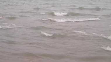 Dalgaların dalgalanan görüntüsü bir göl kıyısına doğru sıçrayıp yuvarlanıyor..