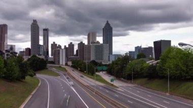 Atlanta, GA - 7 Mayıs 2022: Şehir merkezindeki Jackson Caddesi yakınlarındaki trafik akışı, güneş batıda parlamaya başladığında şehrin ufuk çizgisi üzerinde ağır bulutlar hareket ediyor..