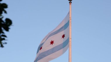 Şikago bayrağının yavaş çekim görüntülerini indiriyorum. Mavi, beyaz çizgili ve kırmızı yıldızlı uzun bir bayrak direğinde sallanan uzun bir bayrak direğinde şehir merkezindeki bir müze binasının üzerinde..