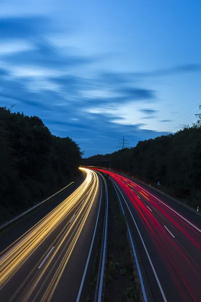 Long time exposure freeway cruising car light trails streaks of light highway electricity pylon sky — Stock Photo, Image