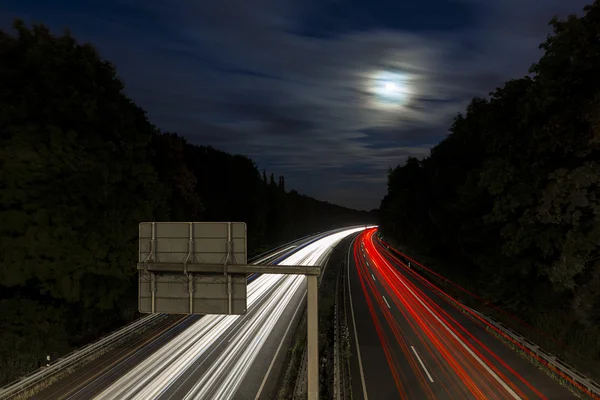 Long time exposure freeway cruising car light trails streaks of light speed highway moon cloudy — Stock Photo, Image