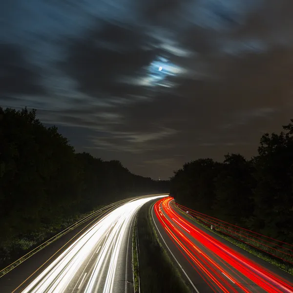 Long time exposure freeway cruising car light trails streaks of light speed highway moon cloudy — Stock Photo, Image