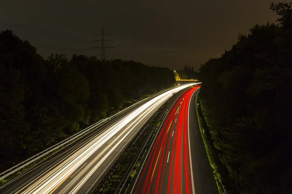 Lungo tempo di esposizione autostrada crociera auto tracce leggere striature di luce autostrada velocità cielo nuvoloso — Foto Stock