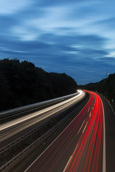 Μεγάλη έκθεση χρόνου αυτοκινητόδρομος πλεύσης αυτοκίνητο φως μονοπάτια ραβδώσεις της ταχύτητα του φωτός στον αυτοκινητόδρομο φεγγάρι θολό — Φωτογραφία Αρχείου