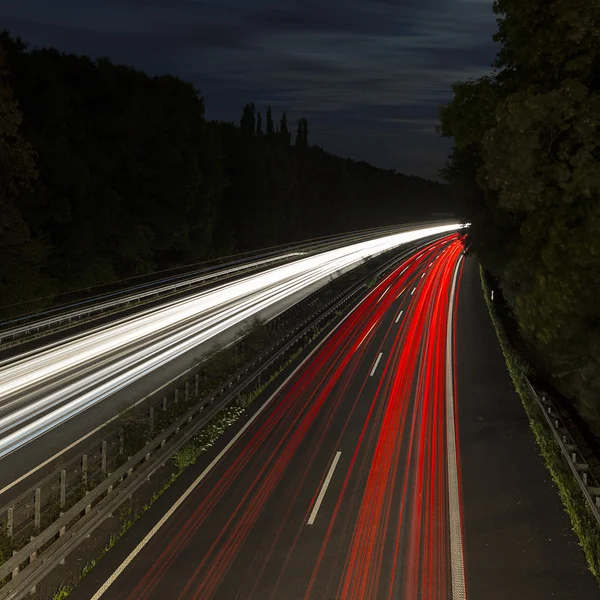Lungo tempo di esposizione autostrada crociera auto tracce leggere striature di luce autostrada velocità cielo nuvoloso — Foto Stock