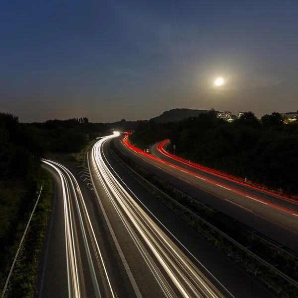 Long time exposure freeway cruising car light trails streaks of light speed highway moon cloudy — Stock Photo, Image