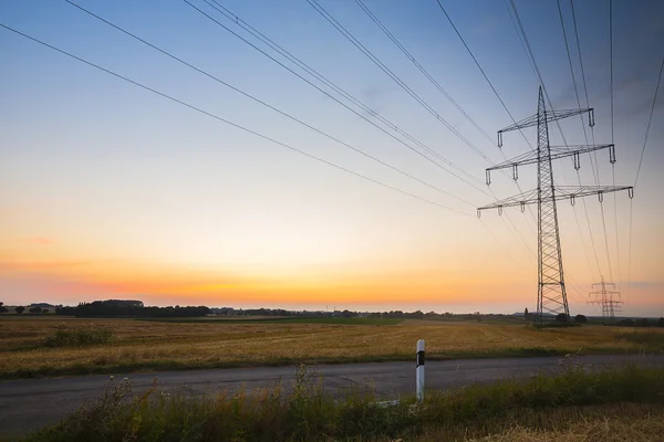 Alta tensão eletricidade pilão pôr-do-sol azul hora energia eletricidade crepúsculo — Fotografia de Stock