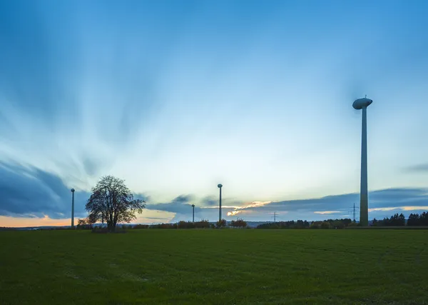 Turbina eólica energia eólica energia eólica rodas de energia eólica campo pôr do sol céu nuvens crepúsculo embaçado — Fotografia de Stock