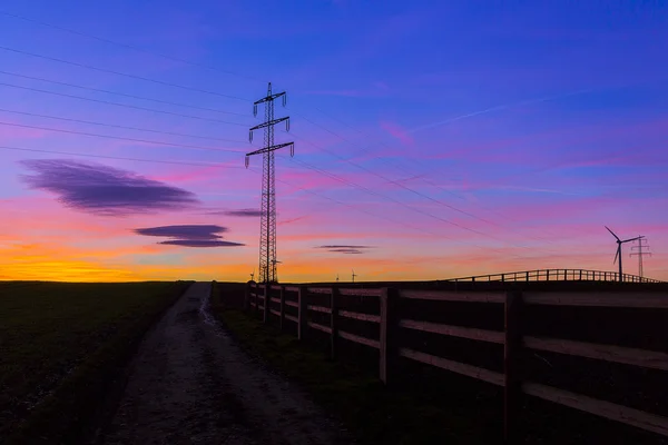 Východ slunce elektřiny pylonu energie větrný mlýn starý dřevěný plot strom silueta přírodní modrá hodina slunce — Stock fotografie