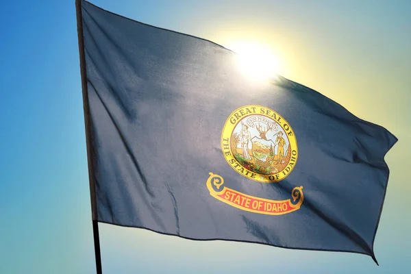 Idaho state of United States flag waving on the wind in front of sun