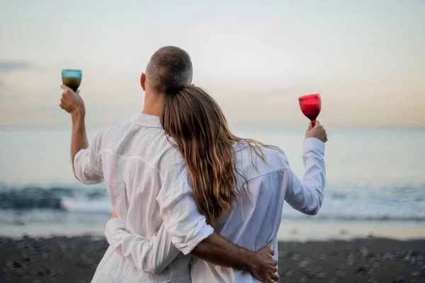 Pareja Joven Abrazándose Una Playa Atardecer Mirando Mar Sosteniendo Una — Foto de Stock