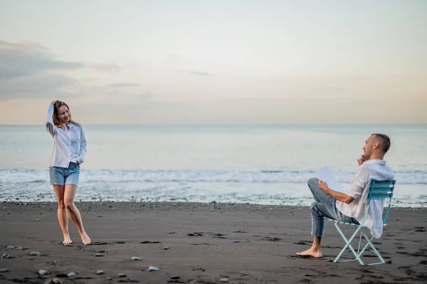 Pareja Joven Una Playa Atardecer Ella Posa Dibuja Foto Alta —  Fotos de Stock