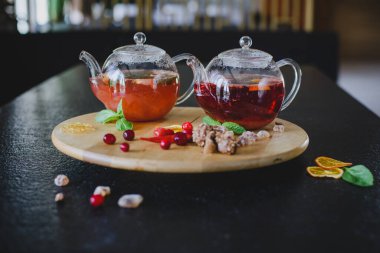 Lokantada dokulu ahşap bir tahtanın üzerinde meyveli çay ile iki çaydanlık. Tatlıların, meyvelerin, meyvelerin ve turunçgillerin yanında.