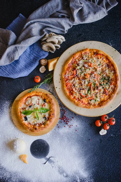 Restorandaki ahşap bir masada pizza fotoğrafı. Üst Manzara. Yakınlarda malzemeler var: peynir, mantar, domates, baharat, un..