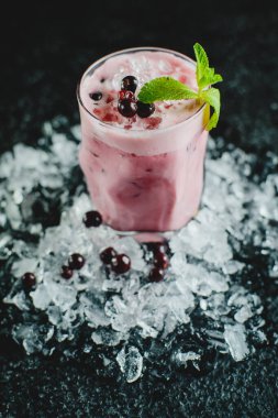 Siyah arka planda buzlu ve meyveli alkolsüz dut kokteyli.