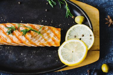 Lokantadaki bir masada limonlu ve kekikli siyah dökme demir bir tavada ızgara somon.