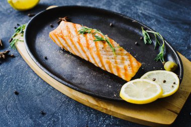 Lokantada siyah bir tavada ızgara somon, limon ve kekik otuyla servis edilir.