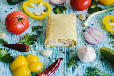 Shawarma, açık sarı lavaşlı, sebzeli ve ahşap ahşap dokulu bir masada et. Kestik. Biber, soğan, sarımsak, maydanoz, bitkiler..