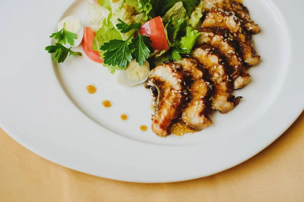 Restoranda masa örtüsüyle kaplı bir masada bir tabak servis edilir. İçinde balık, alet, sos olan bir tabak. Makro