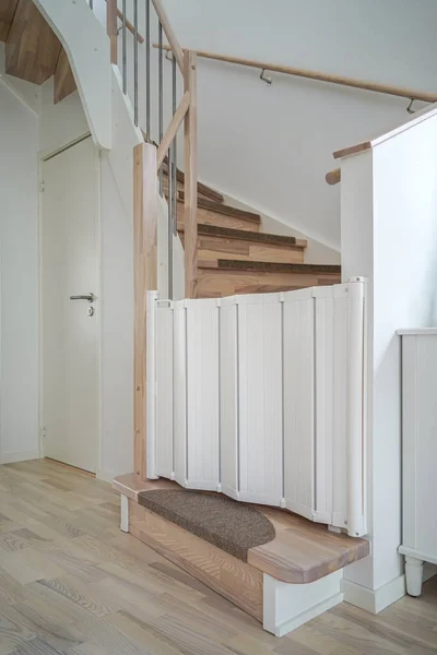 White plastic child safety gate on the wooden stairs