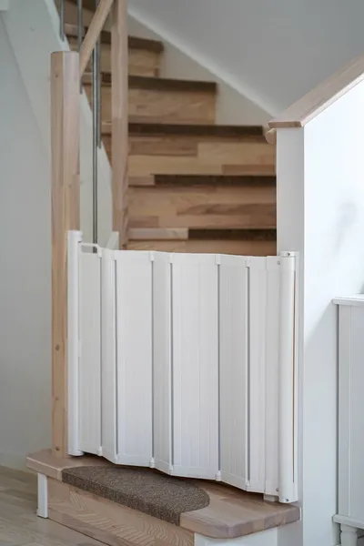 White plastic child safety gate on the wooden stairs