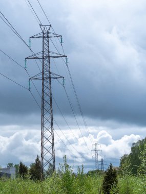 Açık mavi bir arkaplanda yüksek voltajlı elektrik kabloları ve elektrik kabloları.